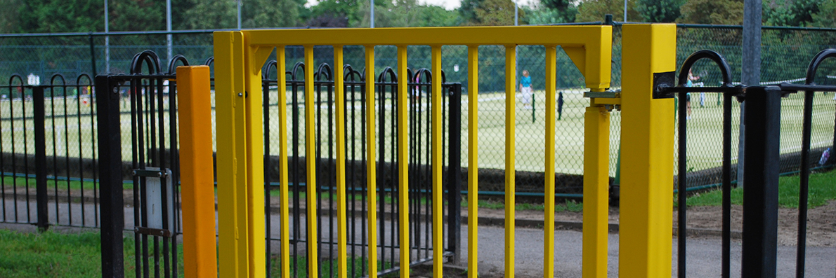 Yellow metal pedestrian gate with hydraulic gate closer